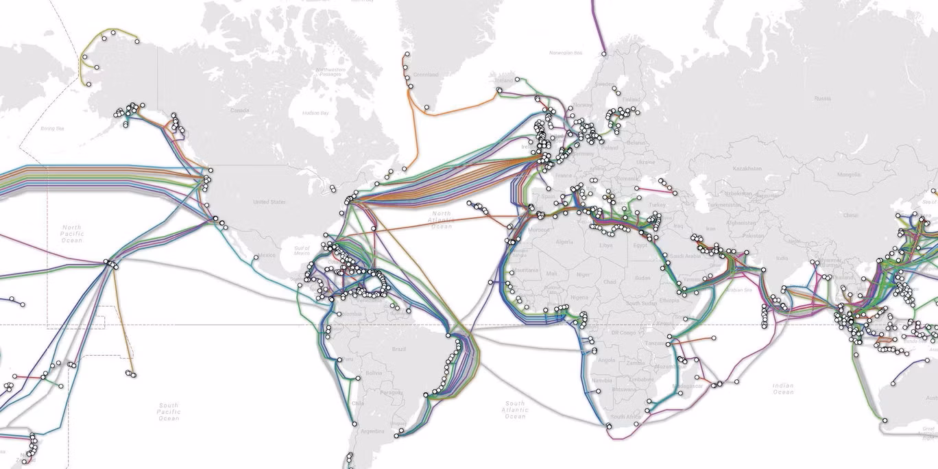 World map of submarine communications cables, with coloured cable routes and white landing-point markers