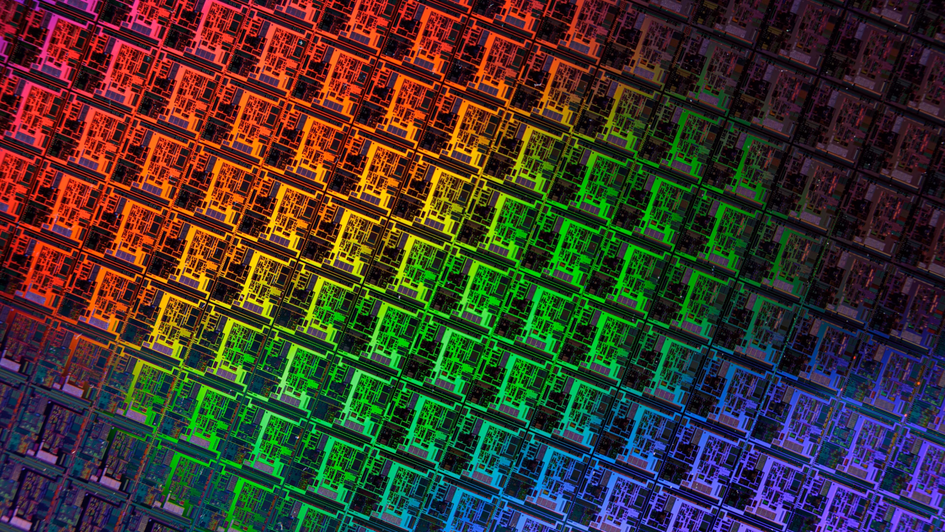 Close-up of a patterned silicon wafer, its grid of identical chip dies shimmering in red, green and blue iridescent colours