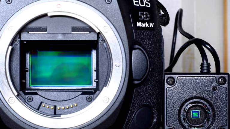 A full-frame CMOS image sensor exposed inside a camera body, beside a much smaller CMOS sensor in a compact camera module