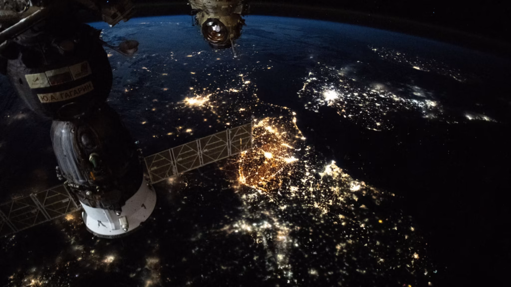 City lights of Europe at night, photographed from the International Space Station with a docked Soyuz spacecraft and solar panel in the foreground