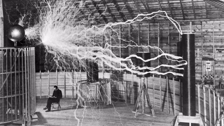 Nikola Tesla seated beside his high-voltage equipment in a c.1899 publicity photograph, a double exposure