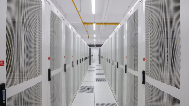 A cold aisle between rows of perforated server-rack doors, with ventilated floor tiles feeding conditioned air