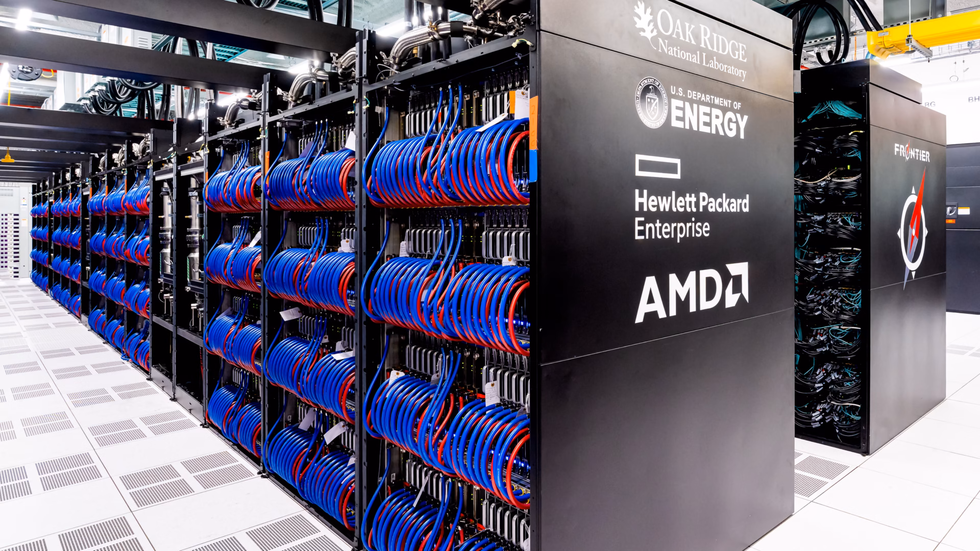 Open cabinets of the Frontier supercomputer, an HPE Cray EX system at Oak Ridge National Laboratory, packed with blue and red coolant hoses