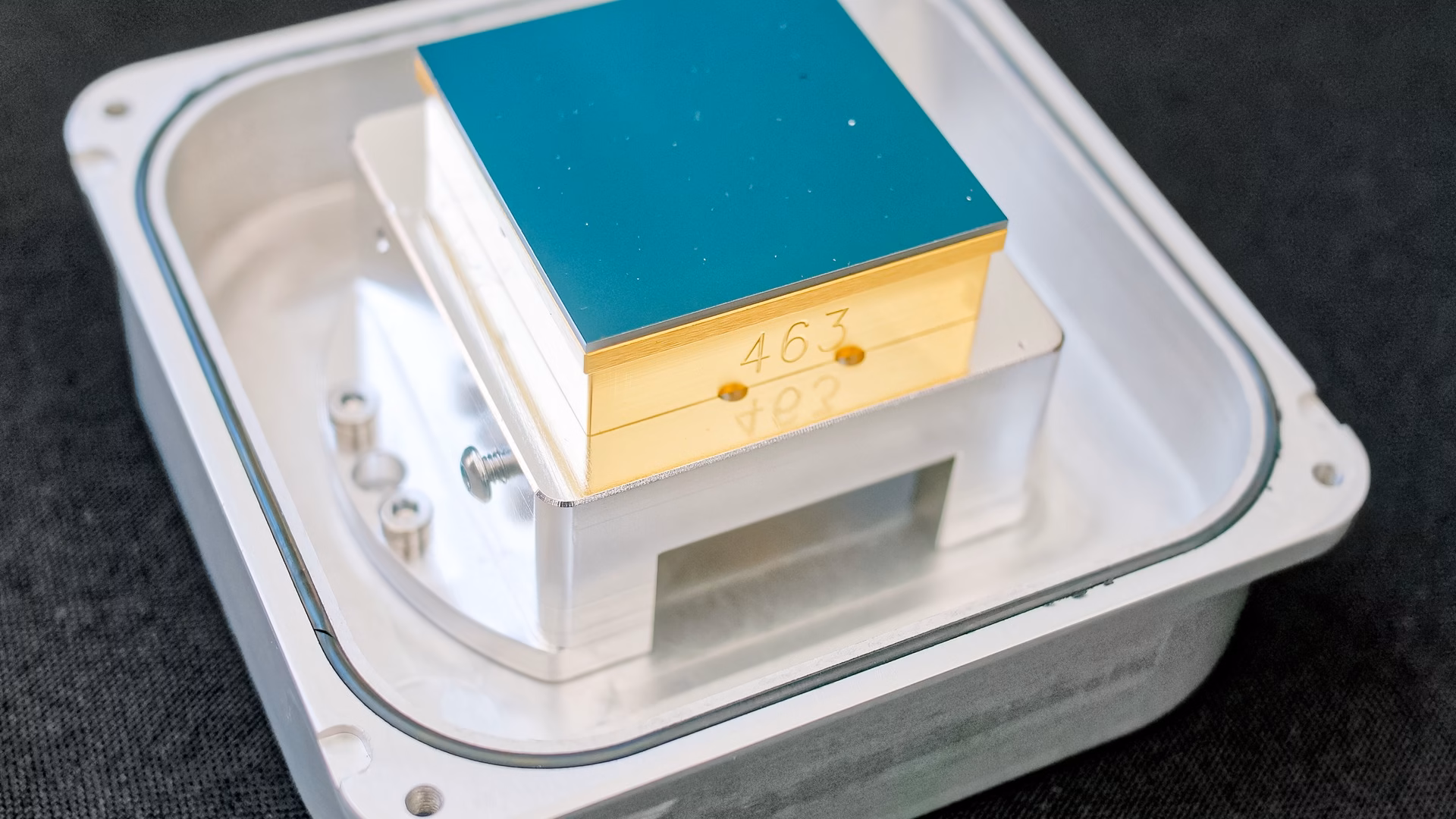 A spare CCD sensor left over from building the Rubin Observatory's LSST Camera, its square imaging surface on a gold-plated mount in an aluminium carrier