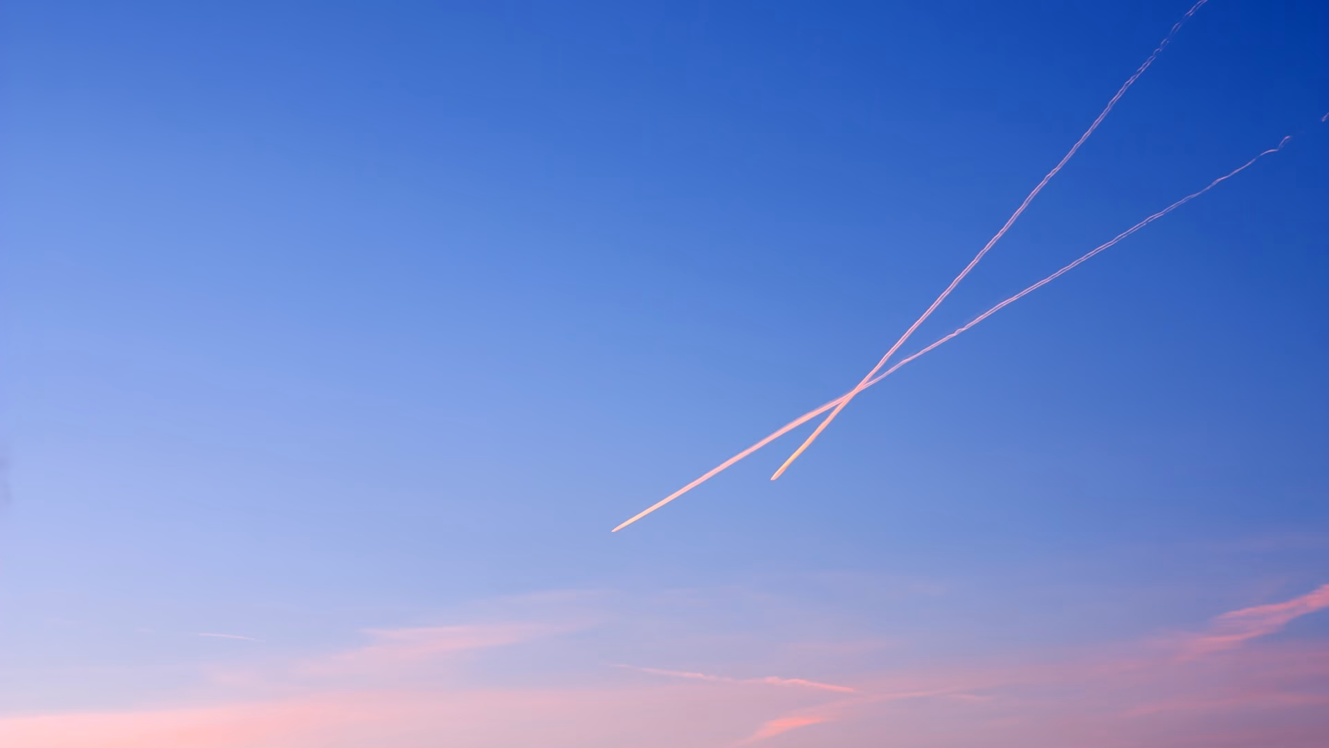Two crossing contrails left by jet airliners in a clear evening sky