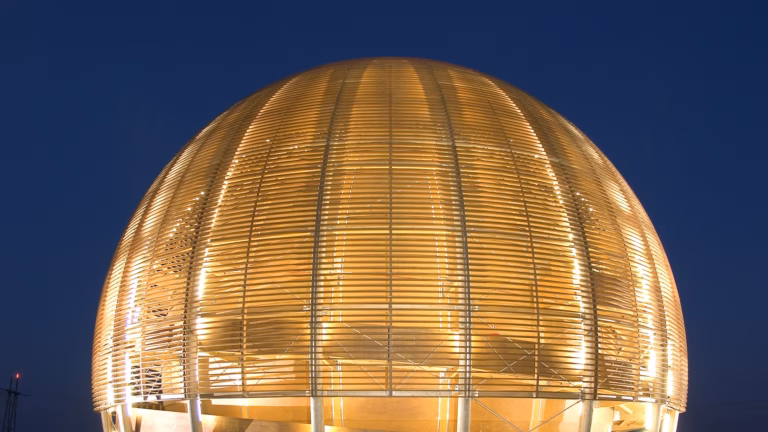 CERN's wooden Globe of Science and Innovation lit up at dusk against a deep blue sky