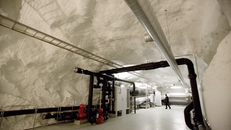 District cooling pipes and pumps along the rock wall of a tunnel at a data centre in Helsinki, Finland