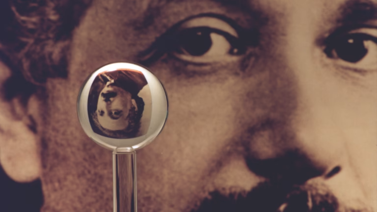A fused-quartz gyroscope rotor from NASA's Gravity Probe B, one of the roundest objects ever made, refracting an inverted image of Albert Einstein from the photograph behind it