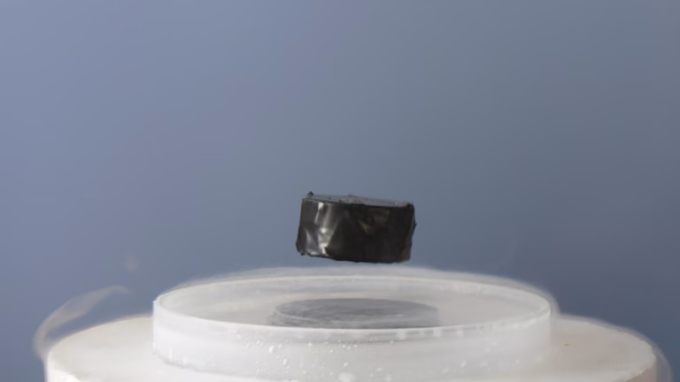 A magnet levitating above a superconductor chilled with liquid nitrogen, the Meissner effect, with cold vapour drifting off the sample