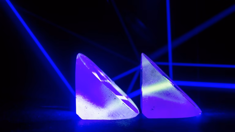 Un raggio laser blu suddiviso in più percorsi da due prismi divisori di fascio, al buio