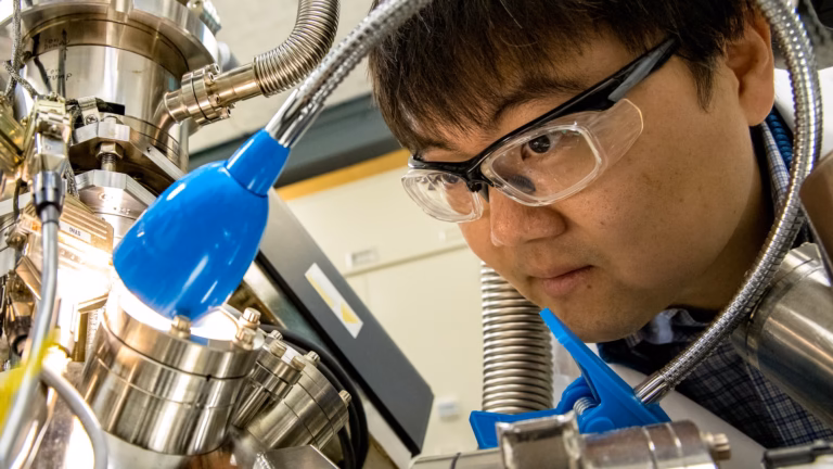 A researcher peers into the vacuum chamber of a four-probe scanning tunnelling microscope, an instrument that works by measuring quantum tunnelling current