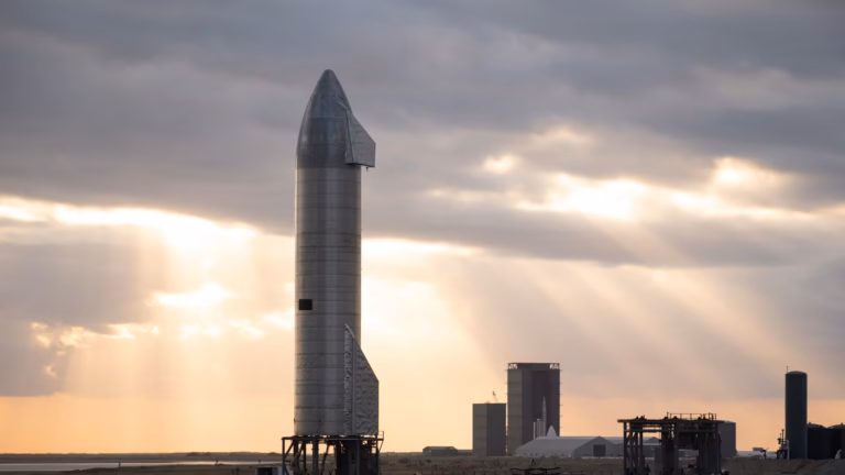 The stainless steel Starship SN9 prototype standing on its launch mount at Boca Chica, Texas, under evening sun rays
