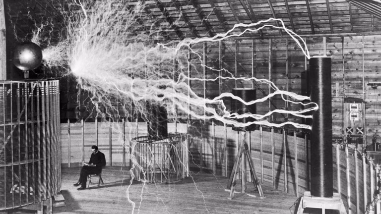 Nikola Tesla seated in his Colorado Springs laboratory as long electrical discharges arc across the room, 1899 (multiple-exposure photograph)