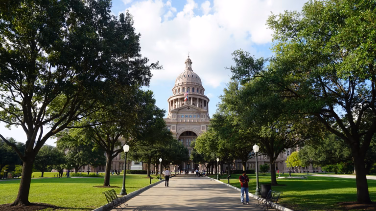 The Texas State Capitol in Austin seen down a tree-lined walkway on the Capitol grounds
