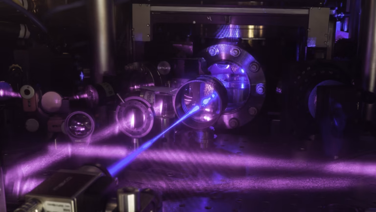 A blue laser beam crosses the optics of JILA's three-dimensional strontium lattice clock, one of the atomic clocks precise enough to register time running at different rates
