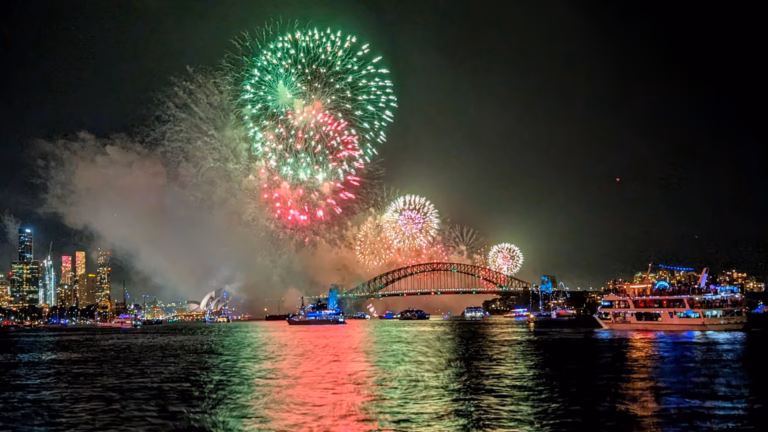 Midnight fireworks over the Sydney Harbour Bridge and Opera House welcoming 2025, reflected in the harbour among spectator boats