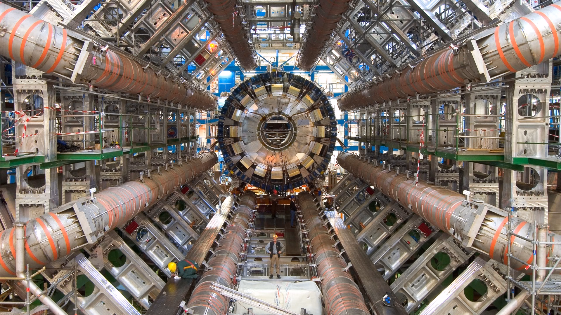 The eight toroid magnets of the ATLAS detector at CERN surround the calorimeter during installation in 2005, with an engineer standing below for scale